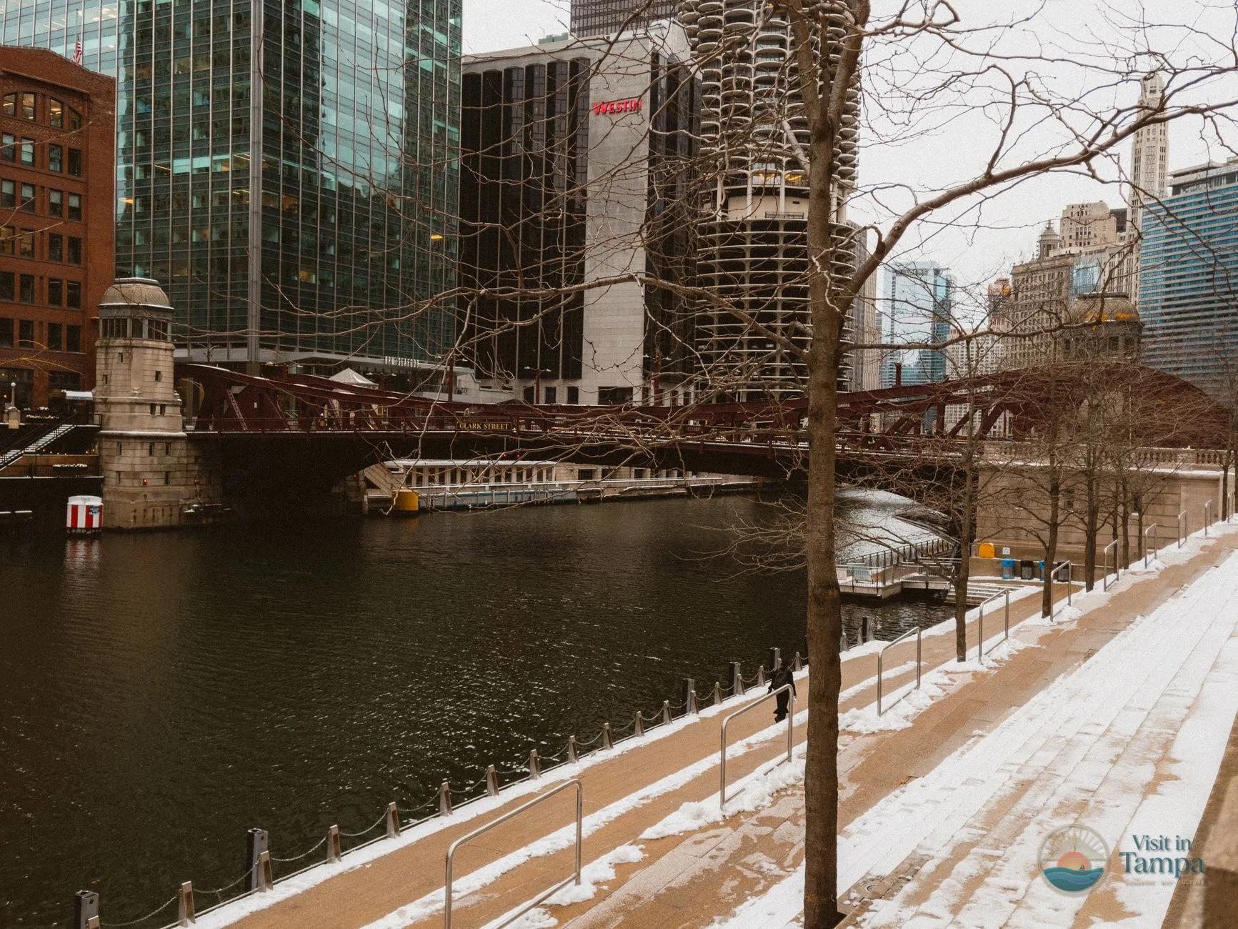 Riverwalk path along the water with downtown buildings behind it
